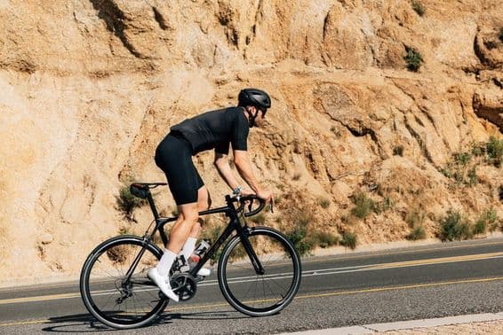 Ciclista em roupa esportiva preta engajado em intenso treinamento ao ar livre.