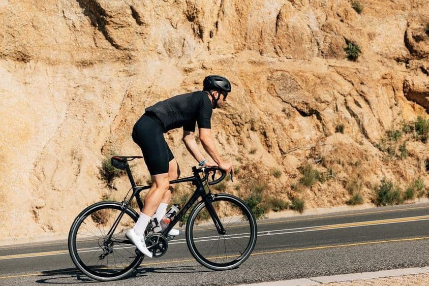 Ciclista em roupa esportiva preta engajado em intenso treinamento ao ar livre.