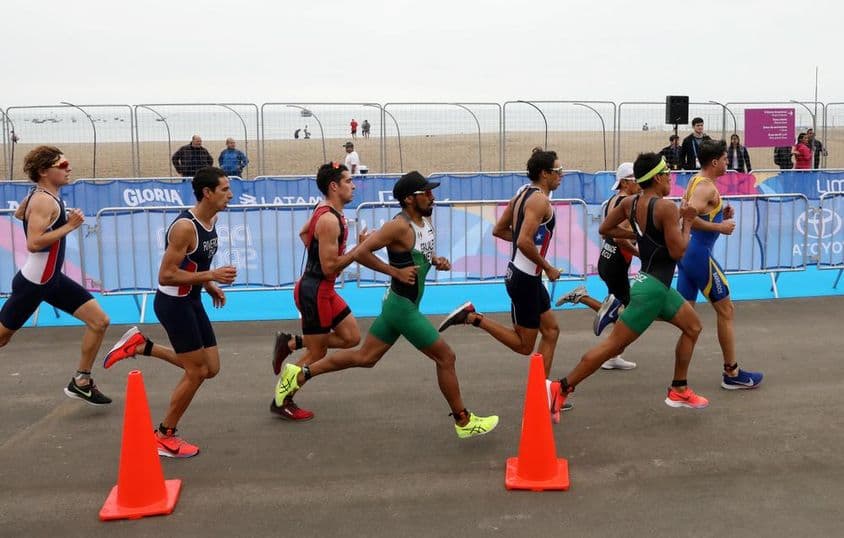 Participantes do triatlo correndo na praia.