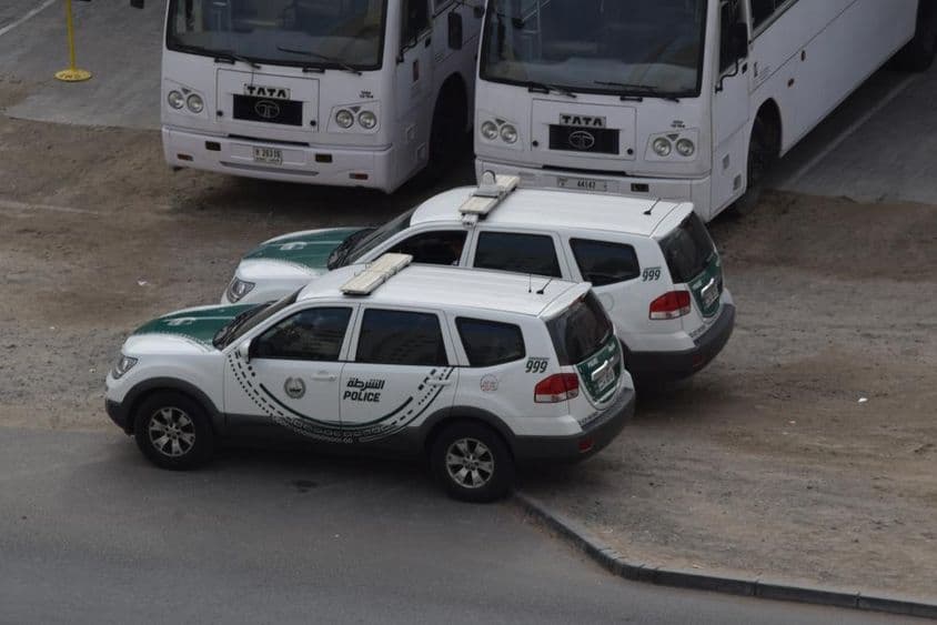 Dois carros de polícia de Dubai estacionados em frente a dois ônibus em Al Quoz, Dubai.