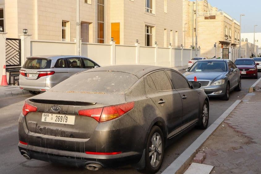 Carros empoeirados e com placa de Dubai estacionados em Abu Dhabi.