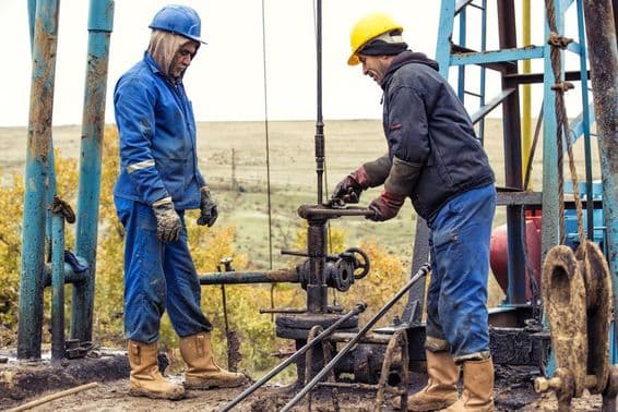 Trabalhadores do petróleo inspecionando uma bomba de petróleo.