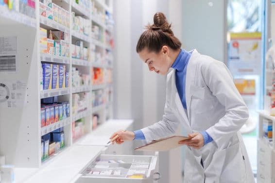 Jovem farmacêutico verificando o estoque de medicamentos em uma farmácia.