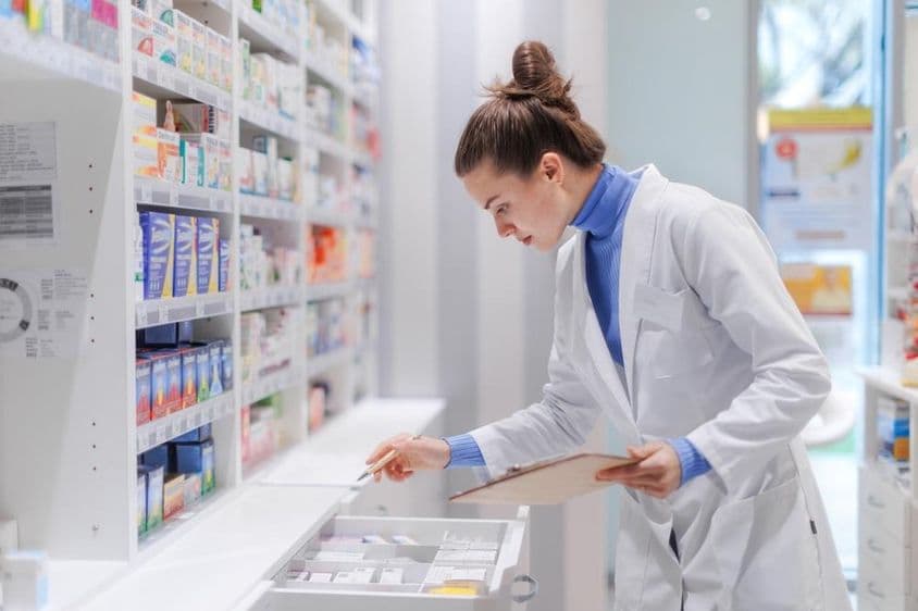 Jovem farmacêutico verificando o estoque de medicamentos em uma farmácia.