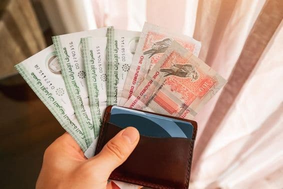 Notas de dirham sendo seguradas com uma carteira.