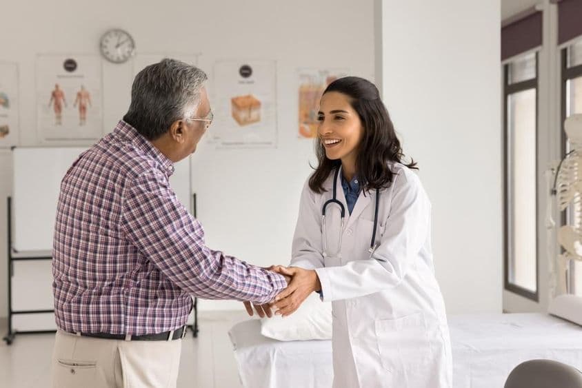 Jovem médica sorridente examinando um paciente.