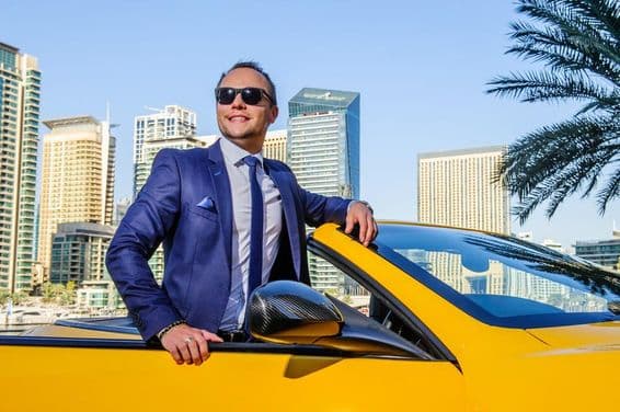 Empresário de sucesso em um carro conversível amarelo.