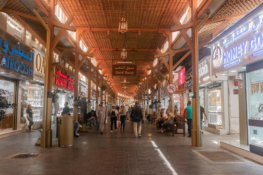 Turistas comprando e explorando o mercado de ouro de Dubai.