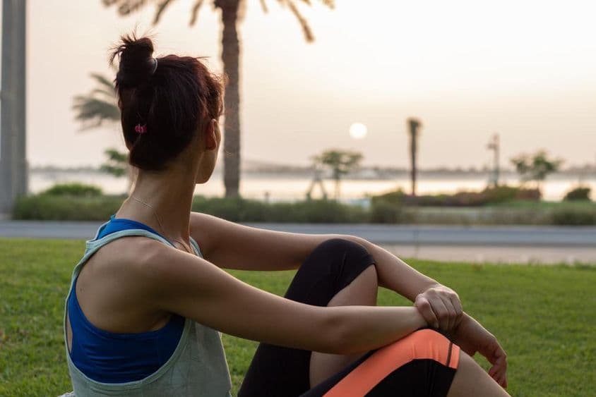 Garota jovem descansando após yoga em um parque na Corniche de Abu Dhabi.