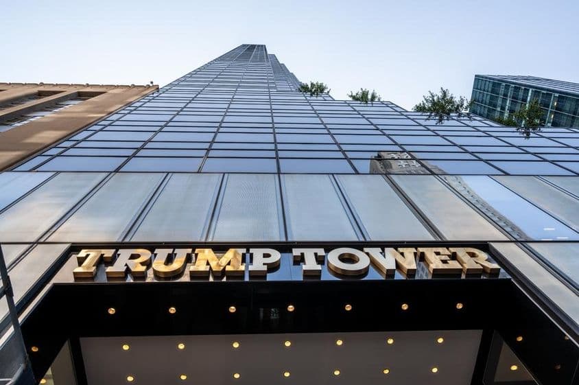 Foto icônica da entrada da Trump Tower destacando a sinalização em metal dourado.
