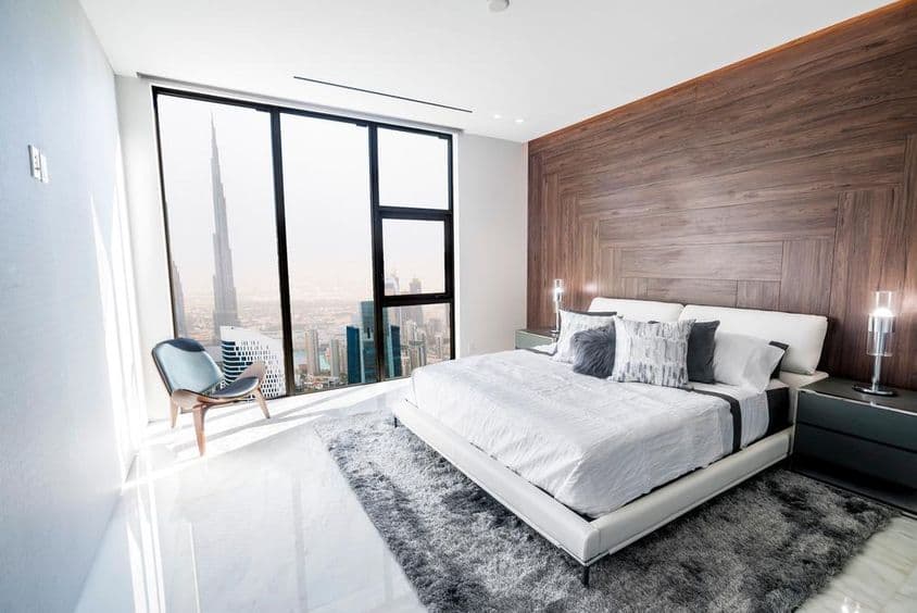 Quarto de luxo com teto branco e acabamento em madeira, com vista para o centro de Dubai.