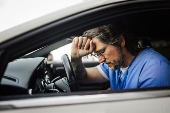 Médico no carro, exausto.
