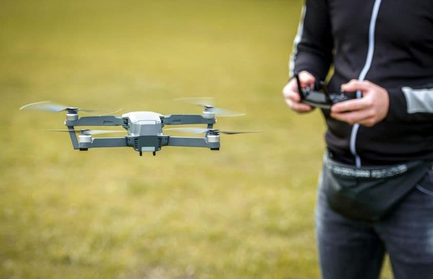 Um homem controlando um drone com um controle remoto.