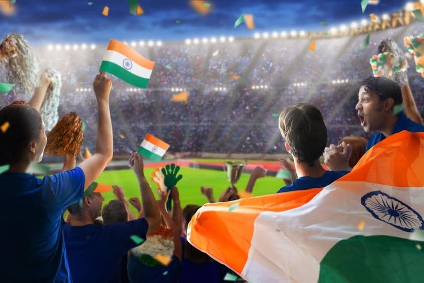 Fãs indianos assistindo seu time jogar críquete no campo.