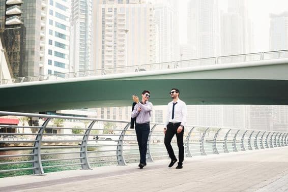 Dois empresários conversando enquanto caminham na Marina de Dubai.