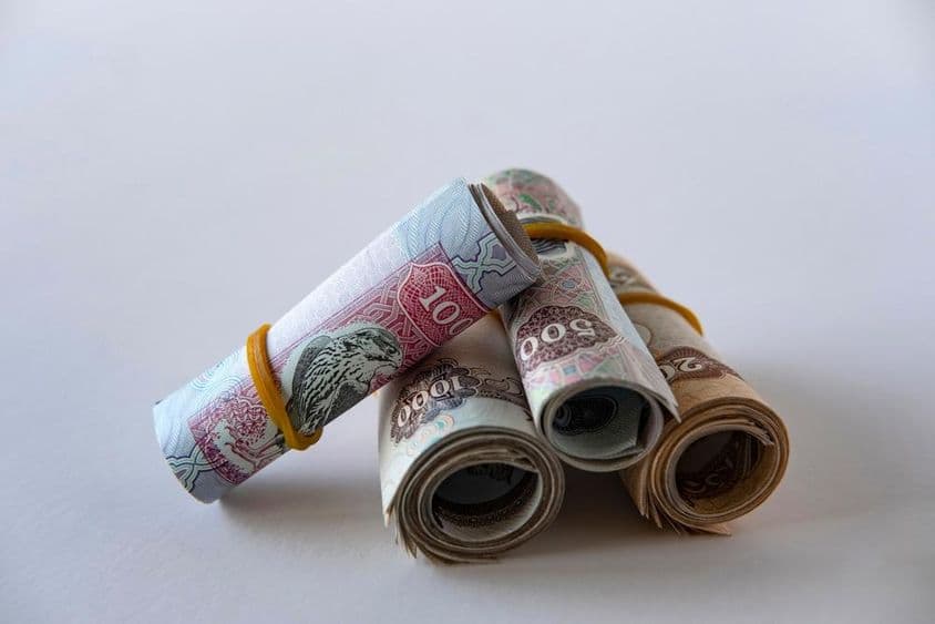 Uma coleção de moeda e moedas de dirham dos EAU enroladas e empilhadas.