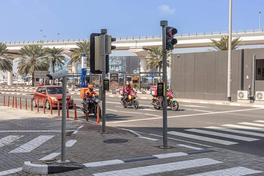 Três motocicletas e um carro parados em uma faixa de pedestres na Sheikh Zayed Road.
