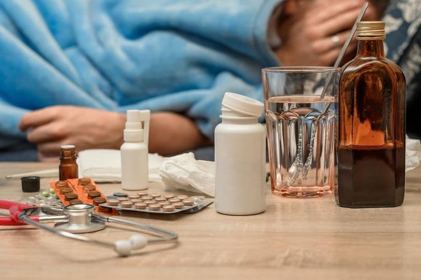 Um homem com um resfriado e febre deitado na cama.