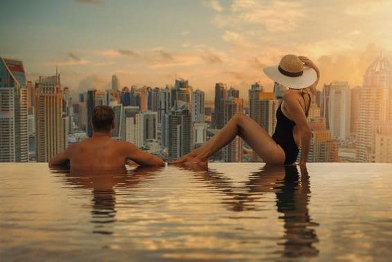 Um casal aprecia o horizonte de Dubai com arranha-céus a partir de uma piscina infinita ao pôr do sol.