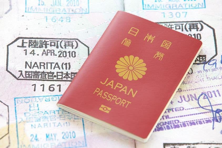 Passaporte japonês com carimbos ao fundo.