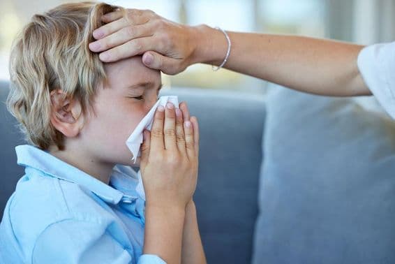 Criança doente com febre no sofá de casa.