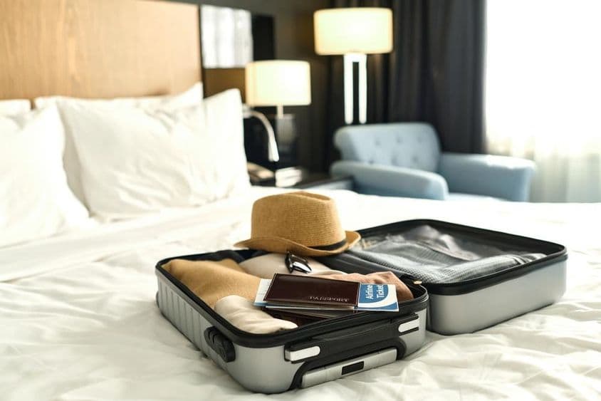 Mala cheia com passaporte e bilhetes em uma cama.