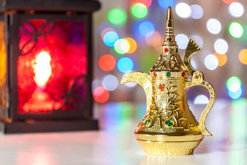 Bule árabe e lâmpada com luzes coloridas e desfocadas ao fundo.