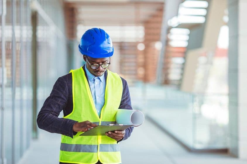 Jovem engenheiro civil analisando estatísticas em papel.