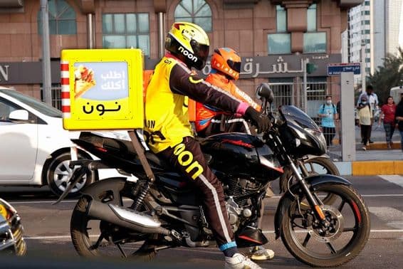 Dubai, homem dos Emirados Árabes Unidos em uma motocicleta para entrega online.