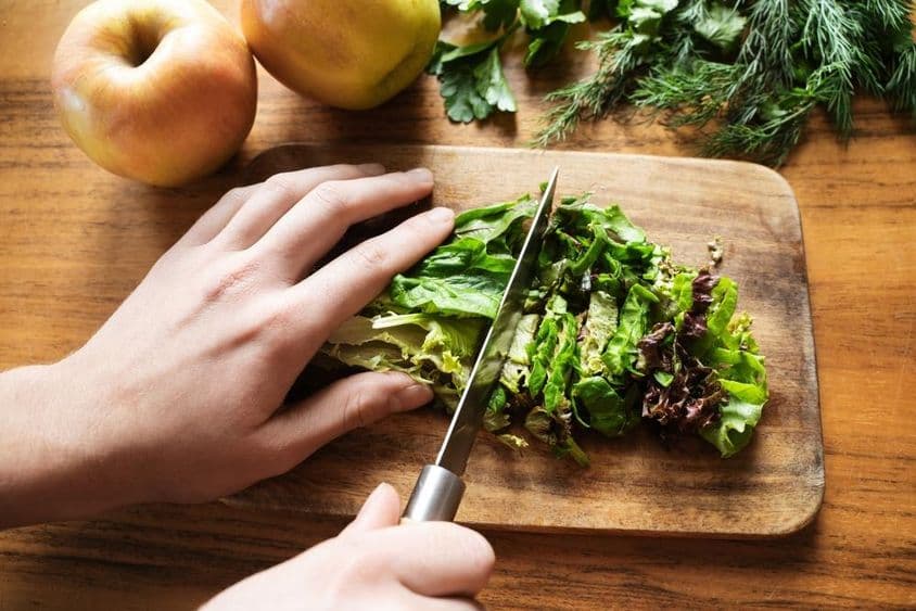 mãos femininas preparando uma salada para o jantar.