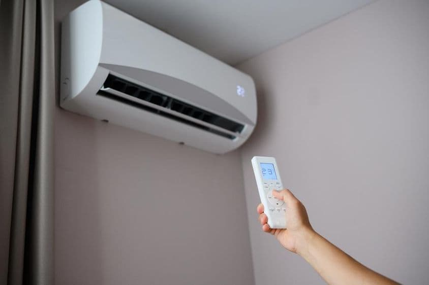 Pessoa ajusta o ar-condicionado para 22 graus Celsius.
