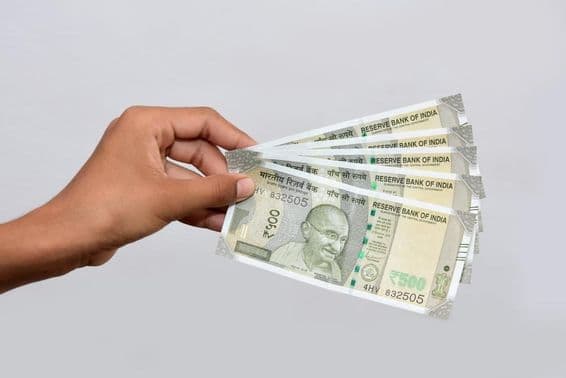 Uma pessoa segura notas de 500 rúpias indianas novas.