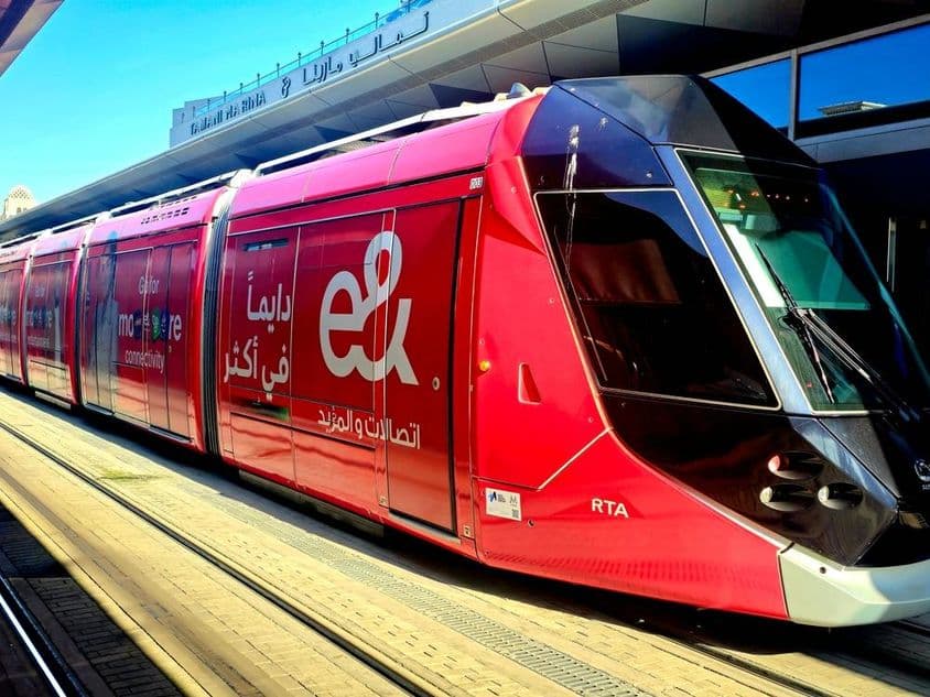 Um tram vermelho estacionado em uma plataforma com grandes janelas e um design elegante.