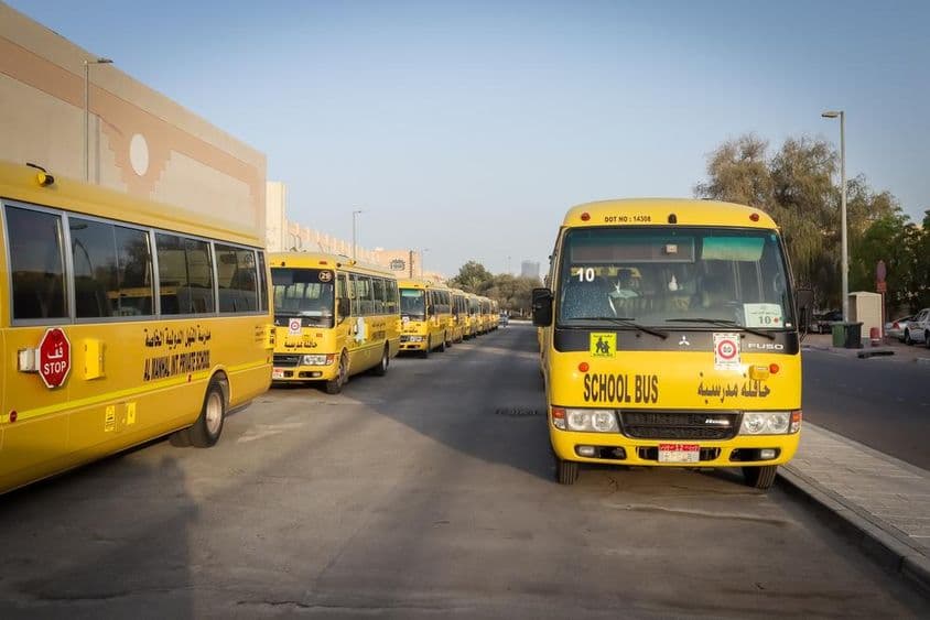 Ônibus escolares amarelos alinhados e estacionados em Abu Dhabi.
