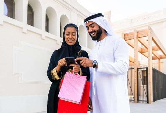 Casal árabe tradicional em traje emiratense namorando ao ar livre.