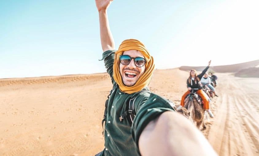 Turista feliz desfrutando de um passeio de camelo no deserto.