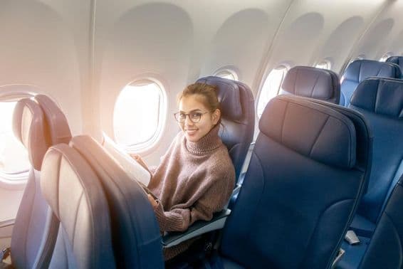 Mulher asiática lendo uma revista em um avião.