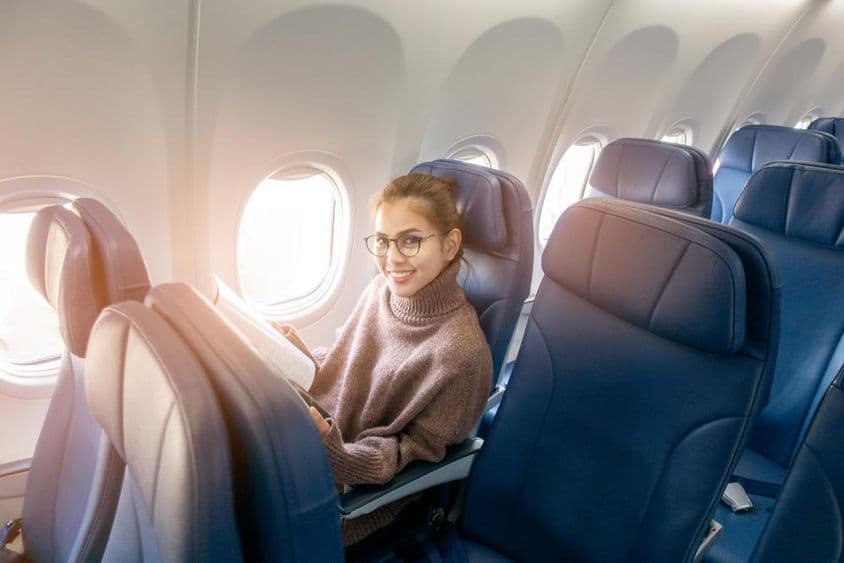 Mulher asiática lendo uma revista em um avião.