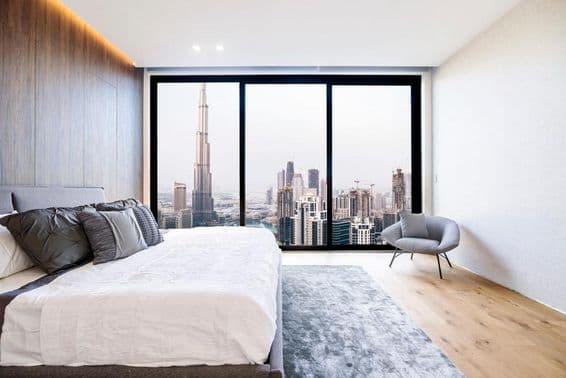 Quarto moderno com teto branco e decoração em madeira, vista de arranha-céus e centro de Dubai.