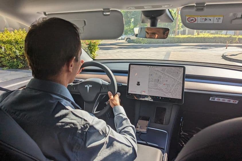 Motorista em Dubai conduzindo um carro Tesla em uma estrada da cidade.