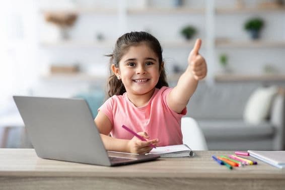 Uma jovem garota árabe faz positivo enquanto aprende em casa com um laptop.