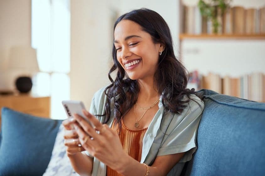 Mulher latina alegre usando um smartphone.