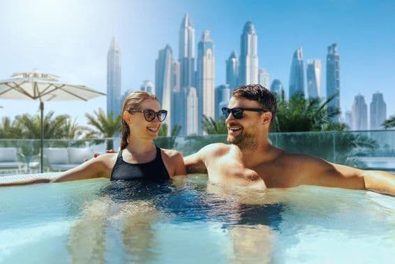 Casal jovem e feliz relaxa em jacuzzi ao ar livre em hotel de Dubai.