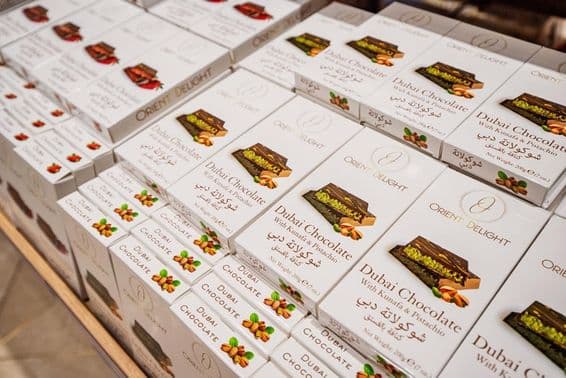 Barras de chocolate de Dubai recheadas com kunafa e pistache empilhadas em uma prateleira de loja.