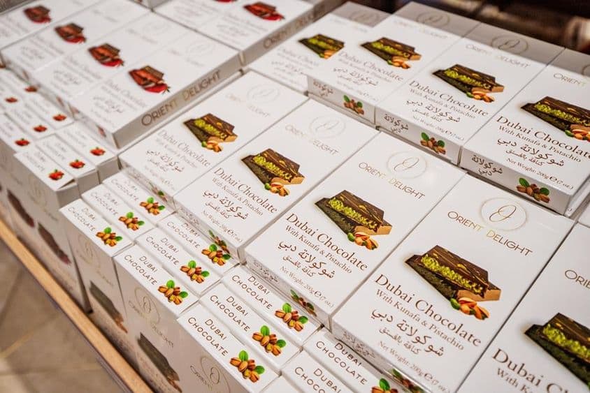 Barras de chocolate de Dubai recheadas com kunafa e pistache empilhadas em uma prateleira de loja.