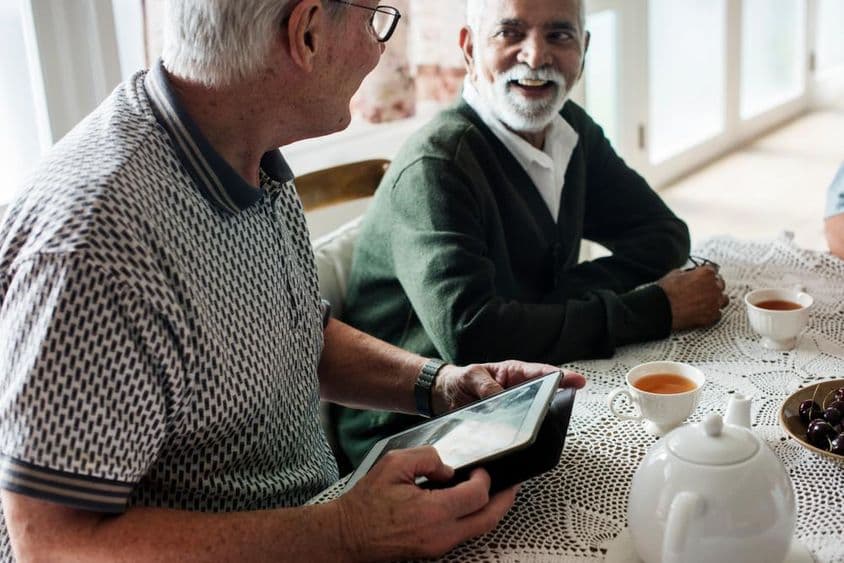Amigos mais velhos olhando um tablet juntos.