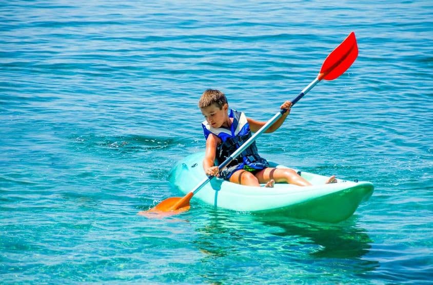 Menino com boia salva-vidas durante aulas de canoagem nas férias de verão.
