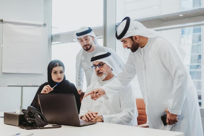 Empresários vestindo trajes tradicionais dos Emirados em uma reunião em um escritório em Dubai.