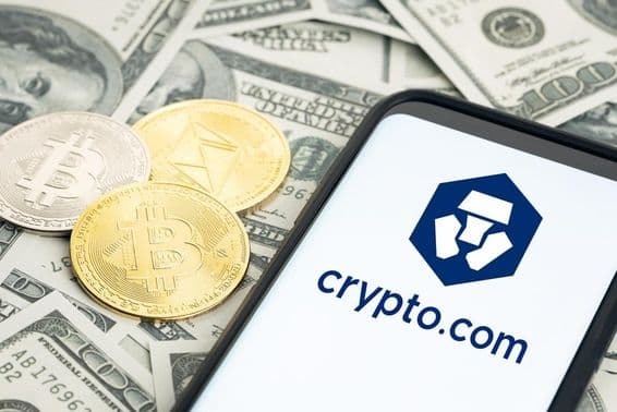 Logotipo da Crypto.com, cédulas de dólar, moedas de Bitcoin e Ethereum visíveis.