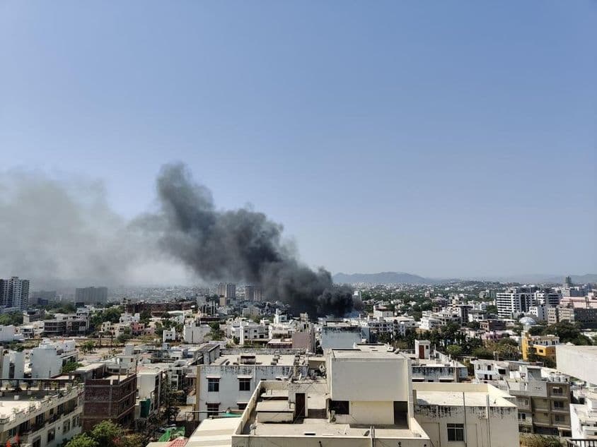 Uma coluna espessa de fumaça negra se erguendo acima da cidade.